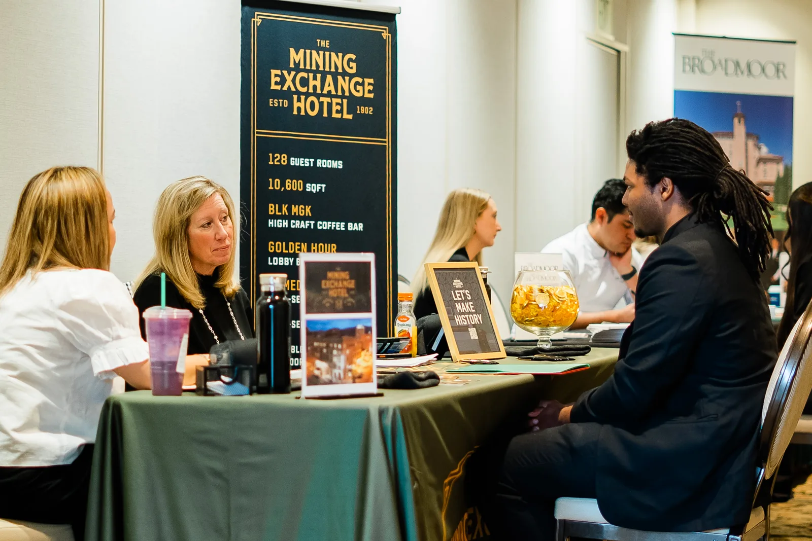 Students interview at a hospitality partner table with Mining Exchange Hotel and Broadmoor signage.