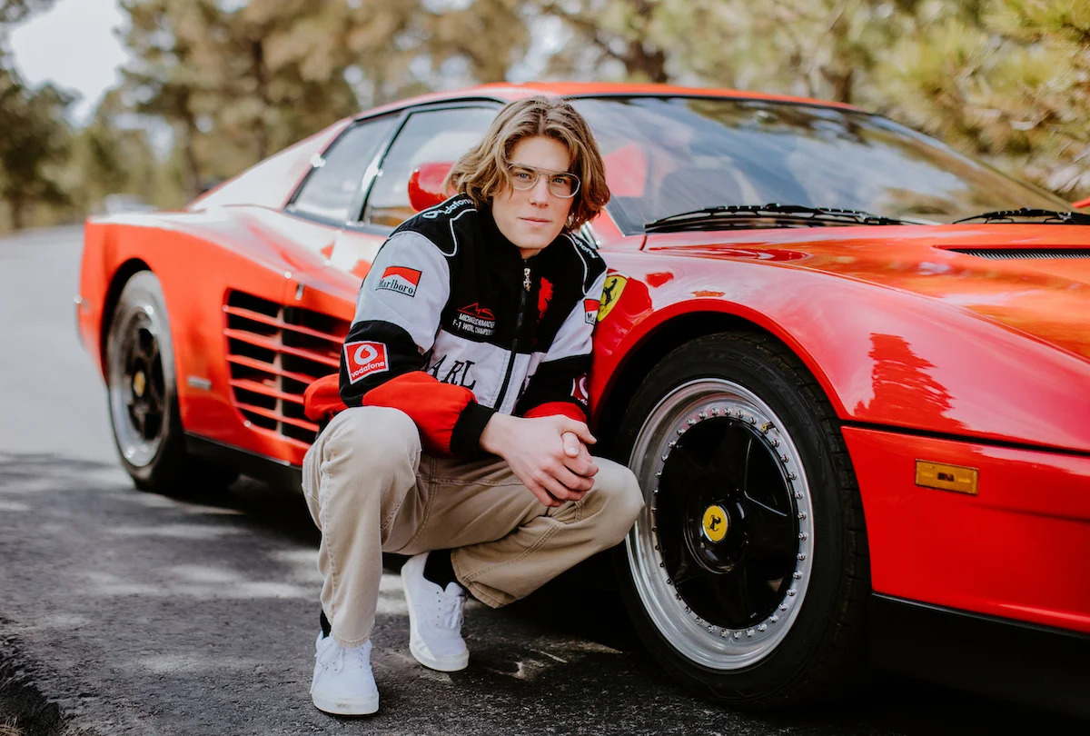 Reilly Crisler crouched beside his red Ferrari Testarossa.