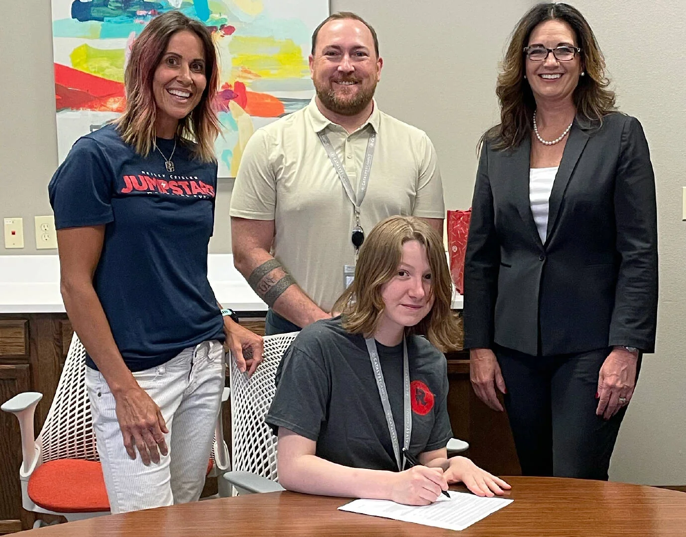 Renee Crisler, wearing a Jumpstart shirt at left, stands with a young person signing on at a Jumpstart event in Colorado Springs.